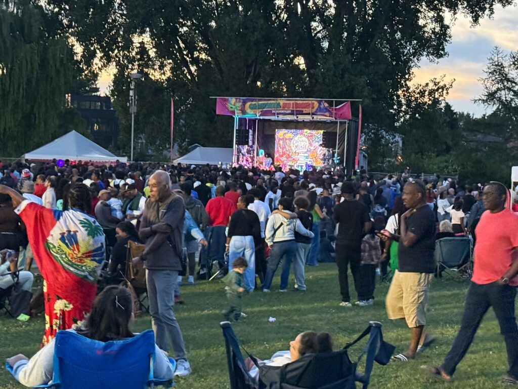 Foule dense devant la scène illuminée au crépuscule